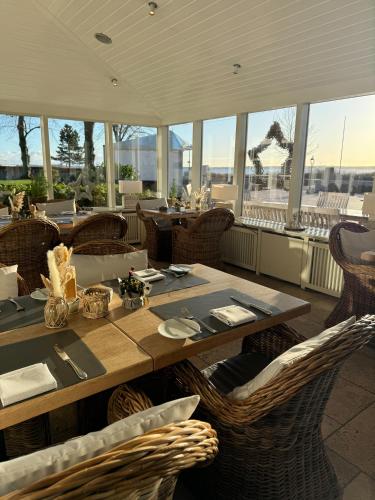 a dining room with a table and chairs and windows at Strandhotel Strande in Strande