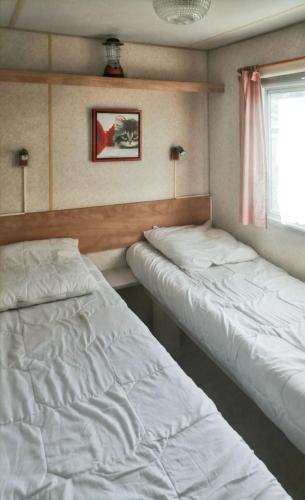 une chambre avec deux lits et une fenêtre dans l'établissement Bungalow charmant à Saint-Pierre-d'Oléron avec jardin clôturé, à Saint-Pierre-dʼOléron