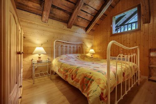 une chambre avec un lit dans une cabane en rondins dans l'établissement Le Myosotis, à Morillon