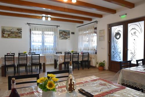a dining room with tables and chairs and windows at Pensiunea Inima Maramureșului in Breb