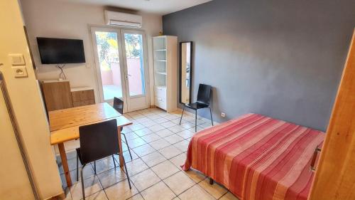 Cette chambre comprend une table, un lit et un bureau. dans l'établissement Studio charmant à Hyères, 20 m², jardin et parking privé, à Hyères