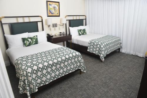 a hotel room with two beds and a table at Courtleigh Hotel & Suites in Kingston