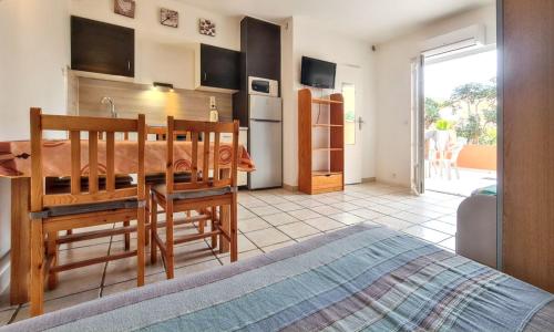 a bedroom with a table and a kitchen with a bed at Studio confortable à Hyères avec terrasse et jardin – 20 m² in Hyères