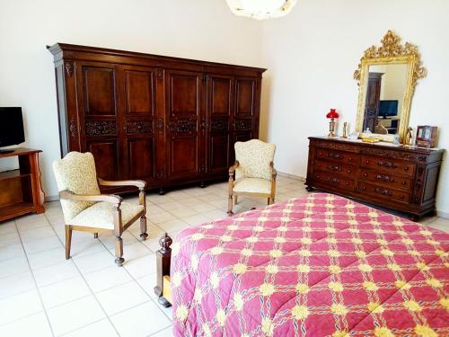 a bedroom with a bed and two chairs and a dresser at Villa Gabry in Floridia