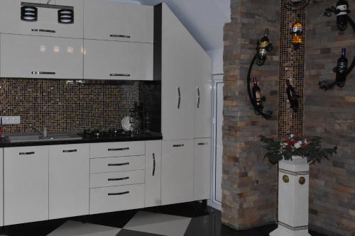 a kitchen with white cabinets and a brick wall at Pensiunea Inima Maramureșului in Breb