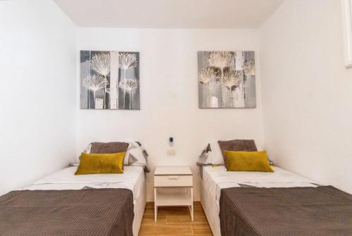 a bedroom with two beds and two paintings on the wall at Cozy apartment in Playa de la Américas, 60 m² with pool in Playa de las Americas