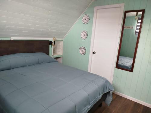 a bedroom with a blue bed and a mirror at Hostal Angy in Pichilemu