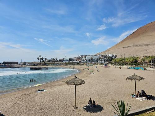 una spiaggia con persone sedute sotto ombrelloni e l'oceano di Alto Mar la Lisera ad Arica