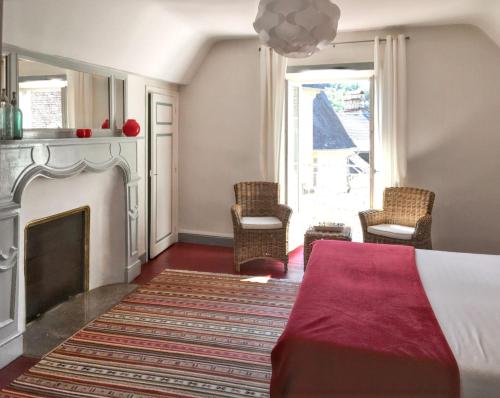 - une chambre avec une cheminée, un lit et des chaises dans l'établissement Maison charmante en Corrèze avec jardin et cheminée, à Corrèze