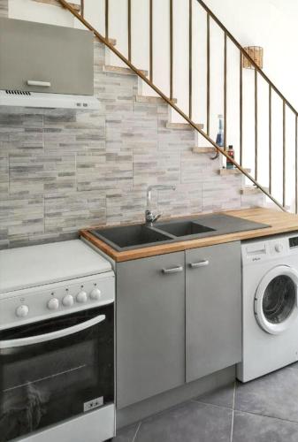 une cuisine avec un évier et une machine à laver dans l'établissement Maison de charme à Vendres avec jardin clôturé, à Vendres