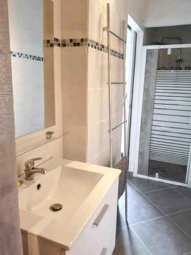 une salle de bain avec un lavabo blanc et une douche dans l'établissement Maison de charme à Vendres avec jardin clôturé, à Vendres