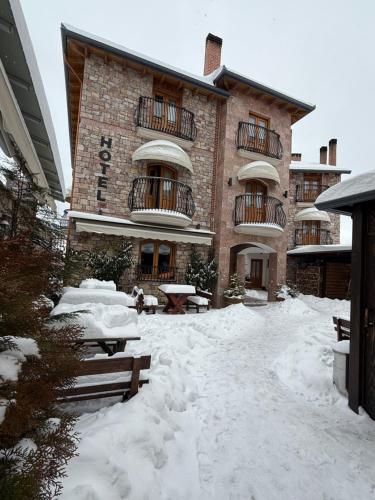 a large building with snow in front of it at Hotel Ambassador Voskopojë in Voskopojë