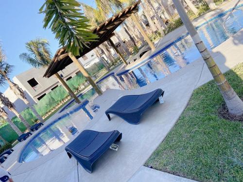 two blue lounge chairs next to a swimming pool at Mazatlan vacation home in Mazatlán