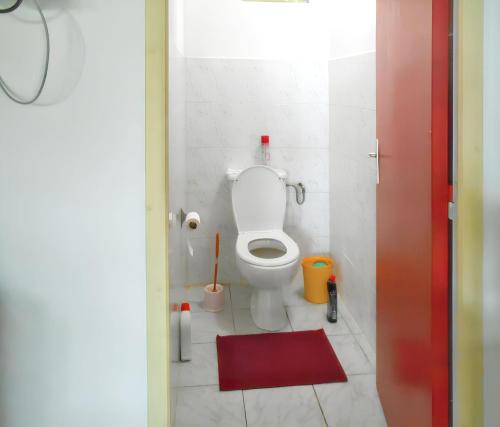 a bathroom with a toilet and a red rug at Bungalow confortable à Deshaies avec vue mer, jardin clôturé in Deshaies