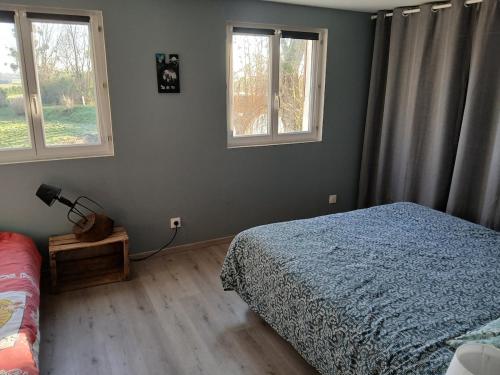 a bedroom with a bed and two windows at Les Terrasses Perchées sur l'Oudon Segré in Saint-Vincent