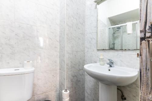 a white bathroom with a sink and a toilet at Alfama Santa Apolonia Apartment in Lisbon