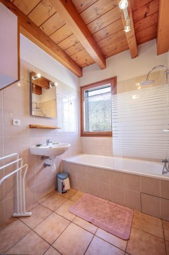 une salle de bain avec une baignoire et un lavabo dans l'établissement Pervenche, à Morillon