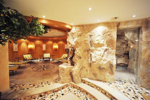 a lobby with a stone wall and tables and chairs at Sporthotel Kirchler in Tux
