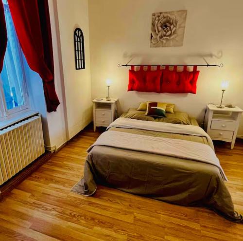 une chambre avec un grand lit avec des oreillers rouges dans l'établissement Les terrasses de Massenet 1, à Néris-les-Bains