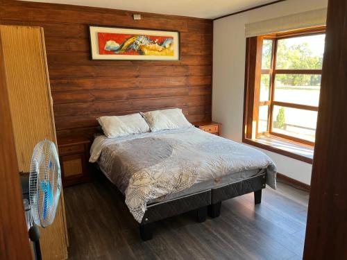 a bedroom with a bed with a fan and a window at Cabaña en Condominio en Pucon in Pucón
