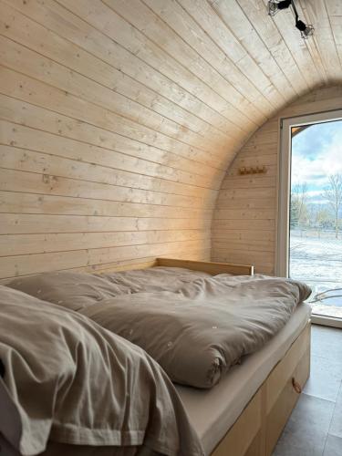a bed in a room with a wooden wall at Dančí zátiší in Nový Oldřichov
