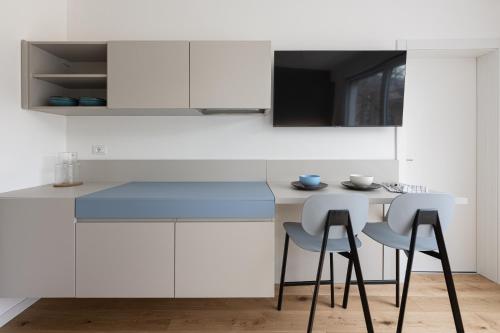 una cucina con armadi bianchi e piano di lavoro blu di Casa Kaleido a Trento