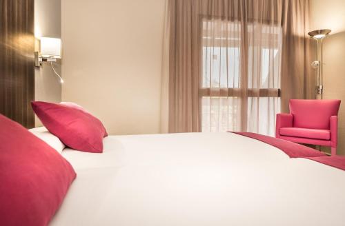 a bedroom with a large bed and a pink chair at Ona Diana Park in Estepona