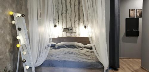 a bed with a canopy in a room with white curtains at Yu&Yu loft apartment in Rīga