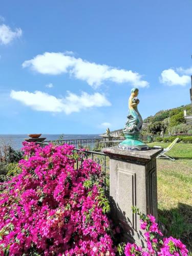 a statue of a woman on a fence with pink flowers at Spacious apartment with sea view in Massa Lubrense in Massa Lubrense