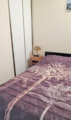 a purple bed in a bedroom with a night stand at Appartement confortable avec vue sur la montagne in Notre-Dame-de-Bellecombe