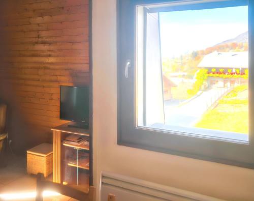 a room with a window and a television on a table at Appartement cosy à Samoëns de 57 m² avec balcon. in Samoëns