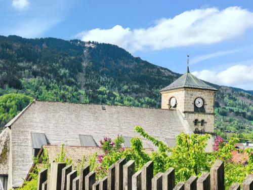 a building with a clock tower and a fence at Appartement cosy à Samoëns de 57 m² avec balcon. in Samoëns