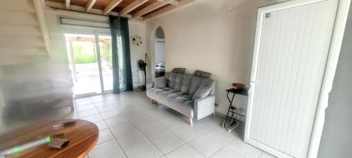 a living room with a couch and a glass door at Maison charmante à Sainte-Anne avec jardin et pergola en bois. in Sainte-Anne