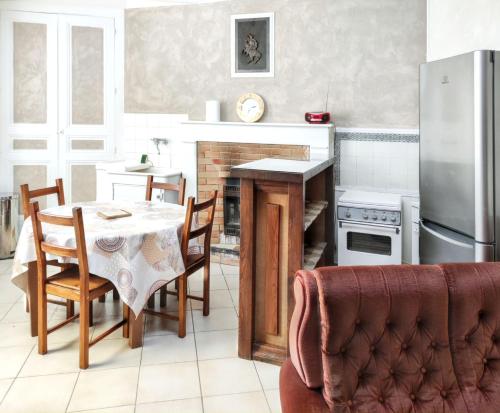 une cuisine avec une table, des chaises et un réfrigérateur dans l'établissement Chaleureuse Maison de Campagne avec Terrasse et Cheminée, à Lignières-de-Touraine