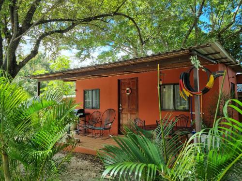 a small red house with chairs and a porch at Pinilla Highlands Incredible mountain views in Tamarindo