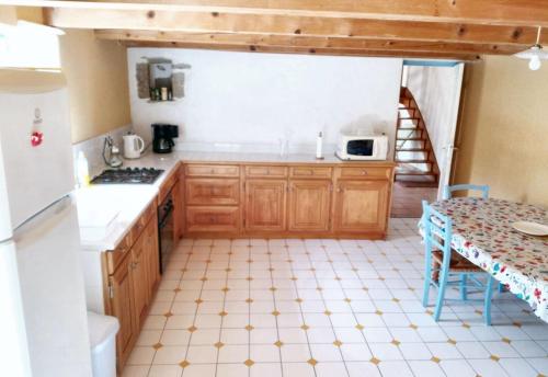une cuisine avec des placards en bois, une table et un comptoir dans l'établissement Maison familiale avec jardin - Plougonvelin, à Plougonvelin