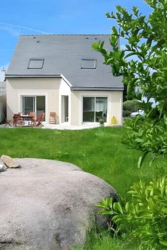 une maison blanche avec une cour avec un champ herbeux dans l'établissement Maison charmante à Perros-Guirec avec terrasse et jardin, à Perros-Guirec
