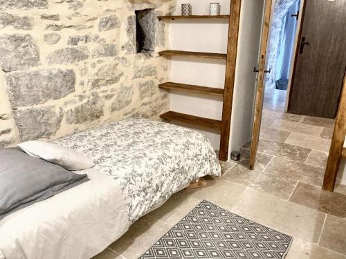 une chambre avec un lit et un mur en pierre dans l'établissement Maison accueillante à Saint-André-de-Cruzières avec piscine partagée, à Saint-André-de-Cruzières