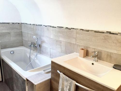 une salle de bain avec un lavabo et une baignoire dans l'établissement Maison accueillante à Saint-André-de-Cruzières avec piscine partagée, à Saint-André-de-Cruzières