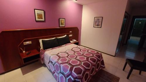 a bedroom with a bed and a pink wall at Motel Montecarlo in Teo