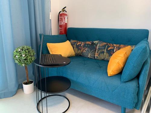 a blue couch with a table with a laptop on it at VILLA HELENA Crystal Apartment in Caniço