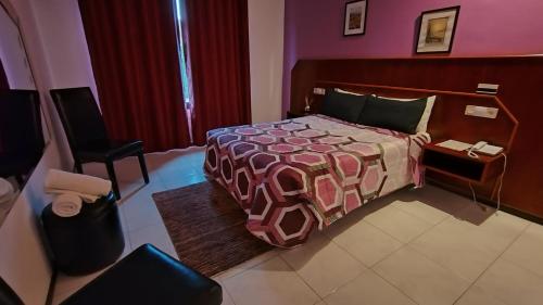 a bedroom with a bed and a chair and a phone at Motel Montecarlo in Teo