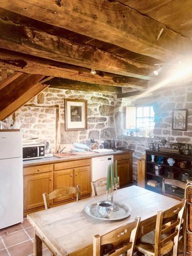 une cuisine avec une table en bois et un réfrigérateur blanc dans l'établissement Maison en granite typique à Chaumeil avec jardin privé., à Chaumeil