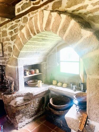 une cuisine avec une arche en pierre et des toilettes. dans l'établissement Maison en granite typique à Chaumeil avec jardin privé., à Chaumeil