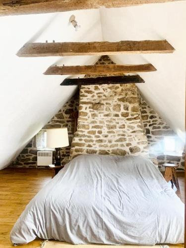 un lit dans une chambre avec un mur en pierre dans l'établissement Maison en granite typique à Chaumeil avec jardin privé., à Chaumeil