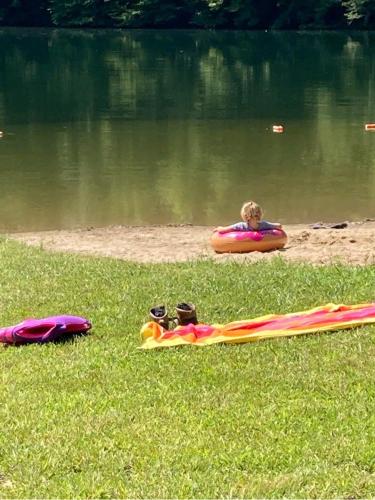 a child is in an inflatable raft on a body of water at Whispering Waters, Hocking Hills, Hot Tub, Pond in Rockbridge