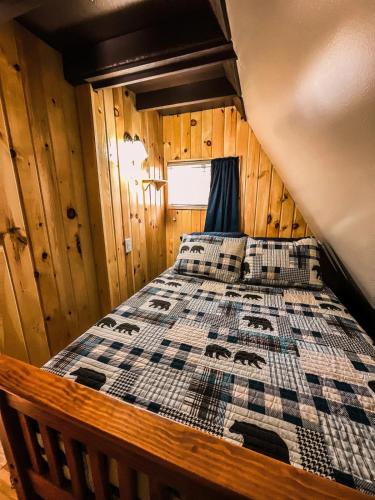 a bed in a cabin with a quilt on it at Whispering Waters, Hocking Hills, Hot Tub, Pond in Rockbridge