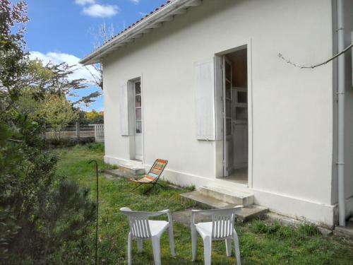 2 chaises et une table devant une maison blanche dans l'établissement Maison charmante à Soulac-sur-Mer avec jardin clôturé, à Soulac-sur-Mer