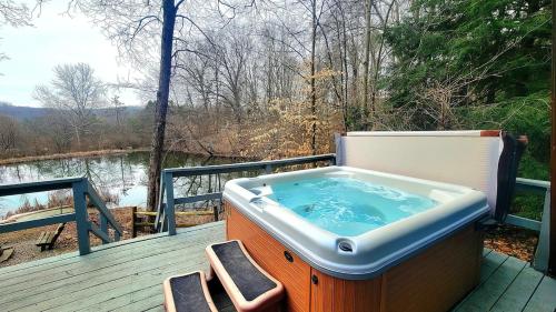 a hot tub on a deck with a view of a river at Whispering Waters, Hocking Hills, Hot Tub, Pond in Rockbridge