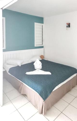 ein Schlafzimmer mit einem großen Bett mit einer blauen Wand in der Unterkunft Charmant appartement à La Trinité avec piscine partagée - 40 m² in La Trinité